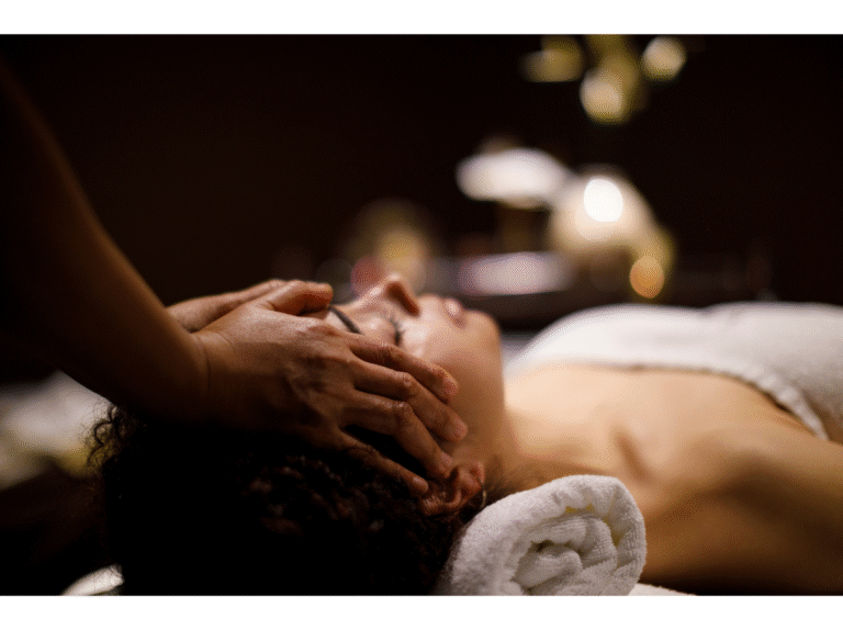 a woman laying in a dark room with candle lights receiving a facial treatment in tranquility.