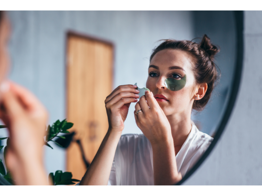 a woman applying eye treatment looking at mirror