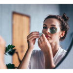a woman applying eye treatment looking at mirror